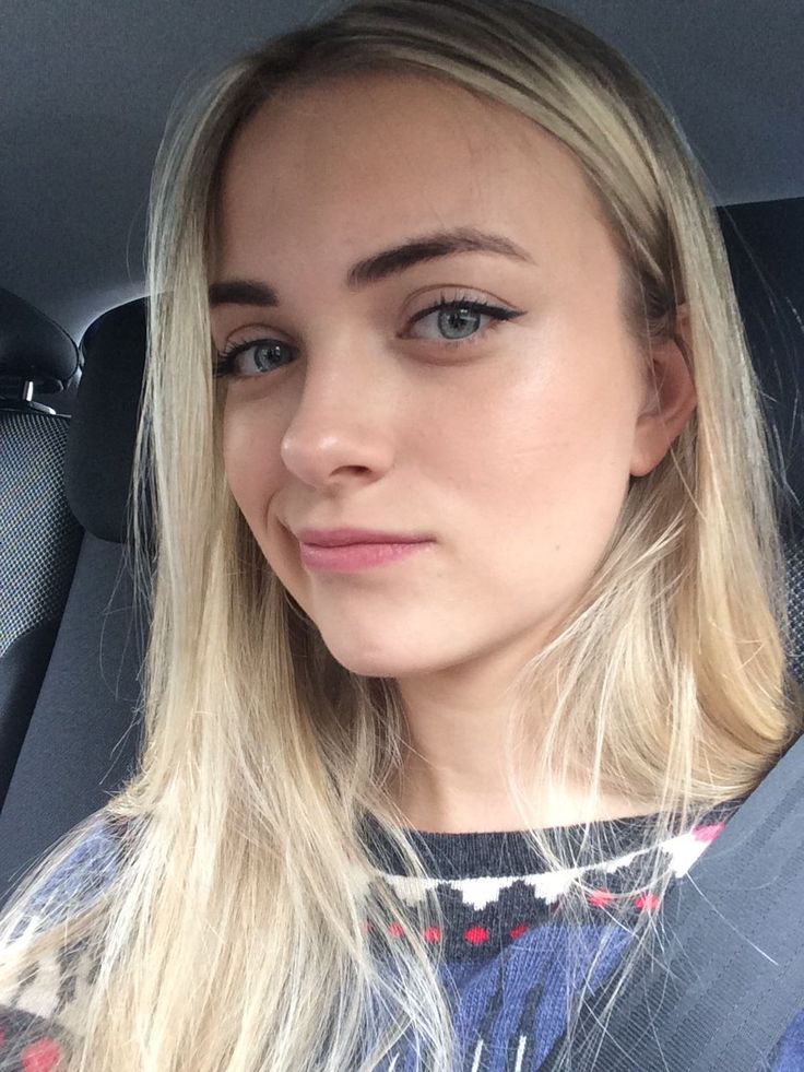 Blonde woman with blue eyes wearing a sweater in a car