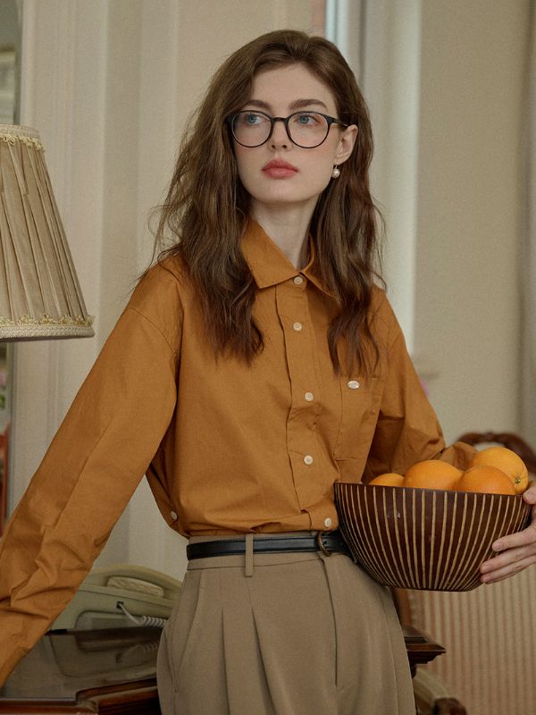 Woman with long hair and glasses holding a bowl of oranges indoors