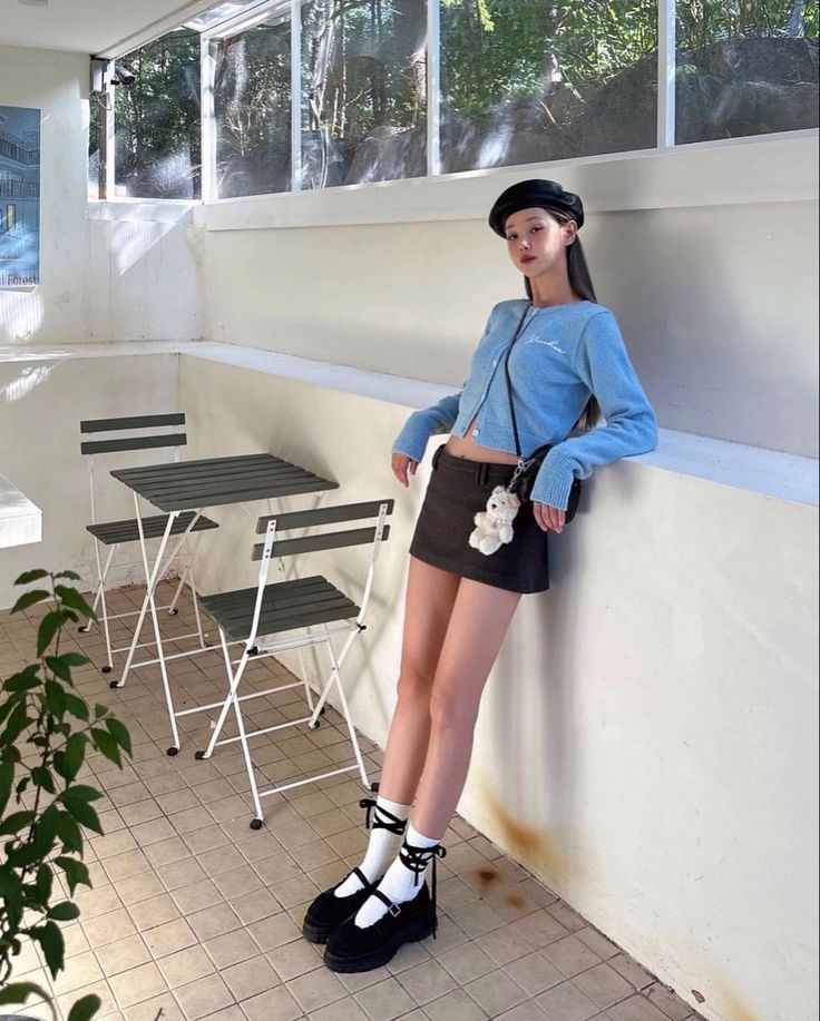Woman in a beret and mini skirt leaning against a wall indoors