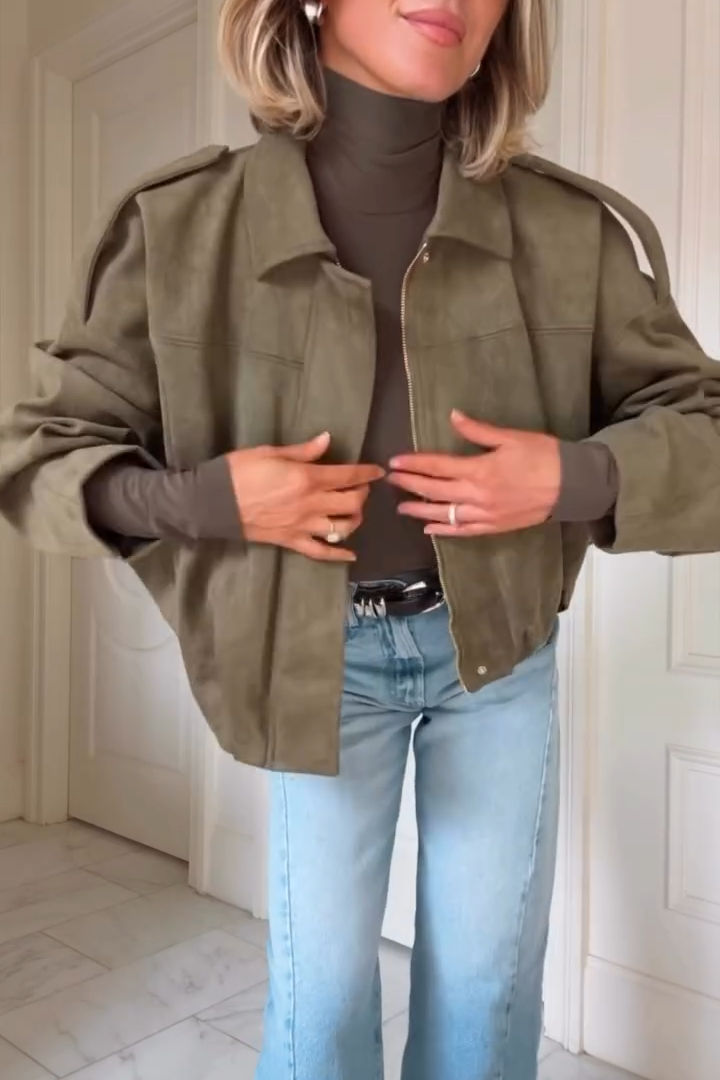 Woman in a khaki jacket and light wash jeans indoors