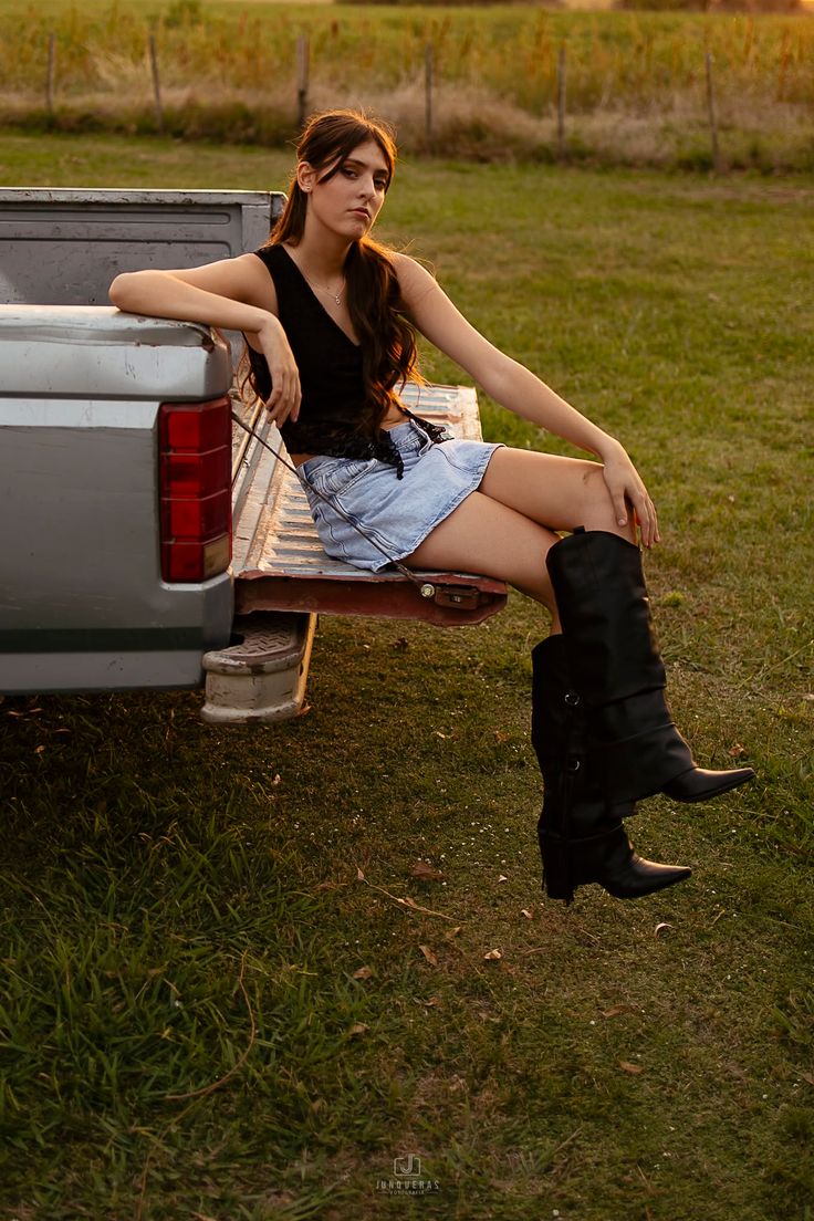 Woman with long hair sitting on the tailgate of a truck at golden hour