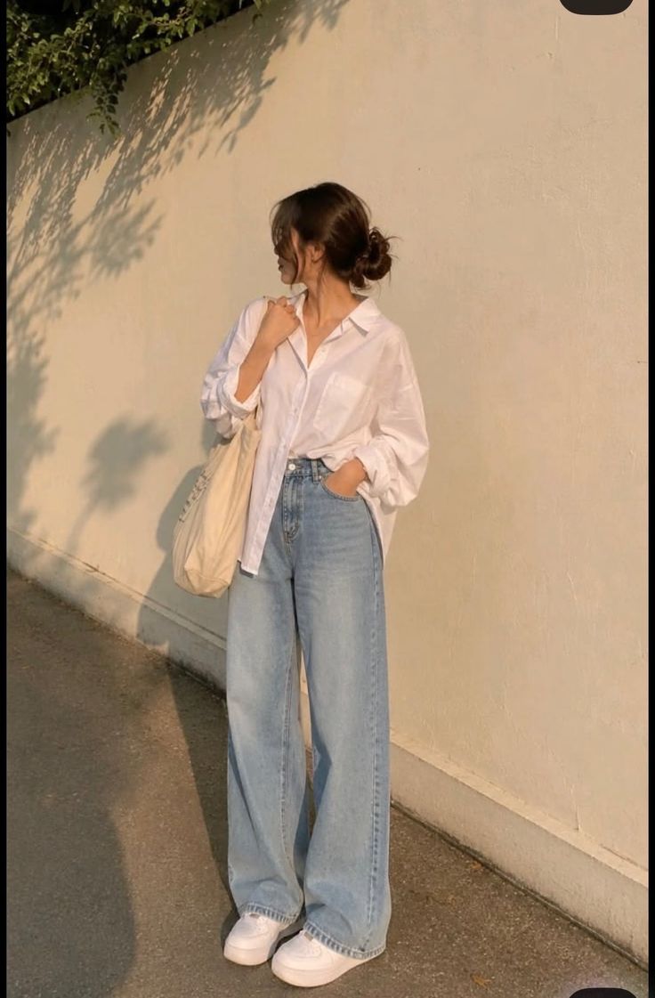 Woman in a white shirt and wide leg jeans with a tote bag outdoors