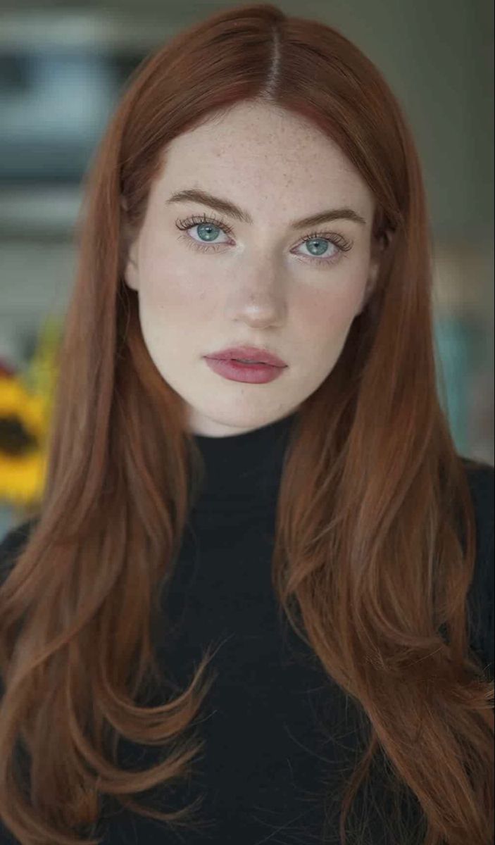 Woman with red hair and blue eyes wearing a black turtleneck