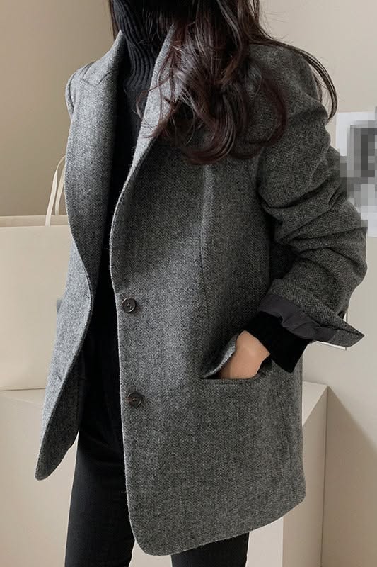 Person in a gray blazer and black turtleneck with long dark hair