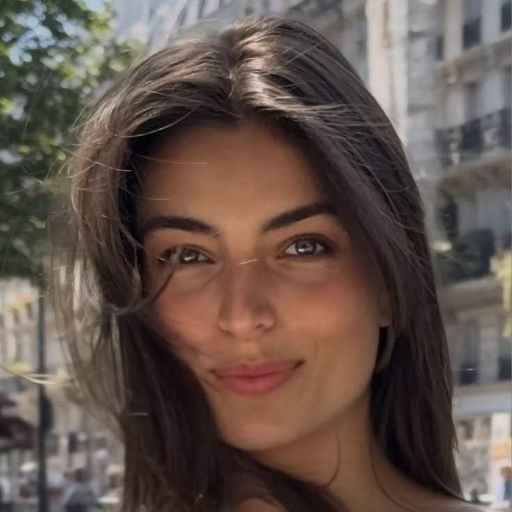 Woman with long brown hair and green eyes smiling outdoors