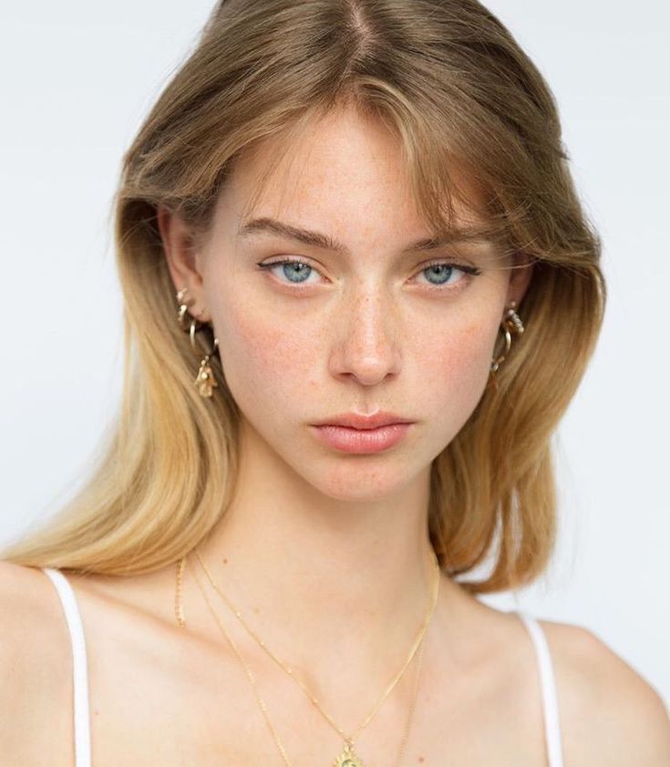 Young woman with blonde hair and blue eyes wearing gold jewelry
