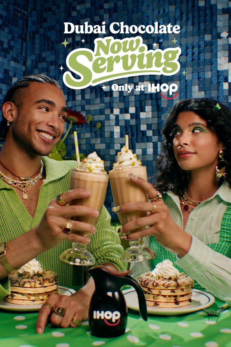Two people toasting with milkshakes and pancakes at a restaurant