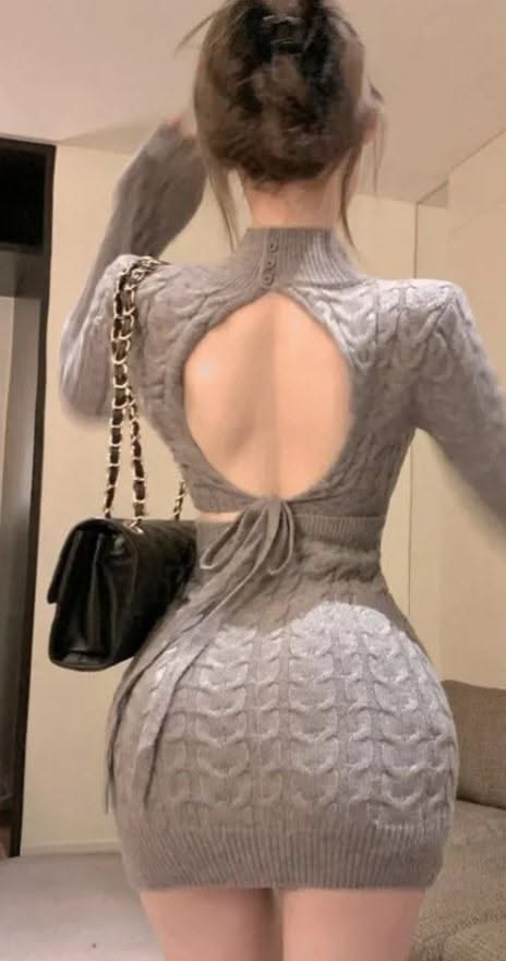 Woman in a gray knitted mini dress with an open back and black handbag
