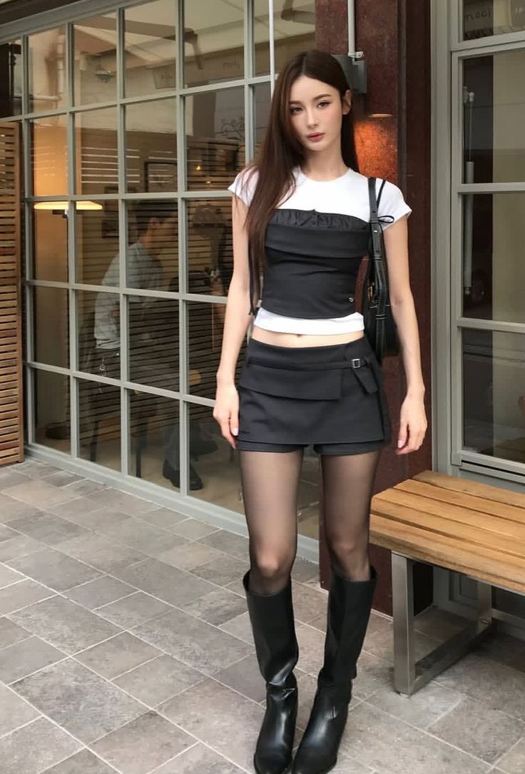 Woman with long hair wearing a crop top, mini skirt, and black boots outdoors