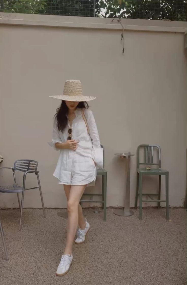 Woman in a straw hat, white shirt, and shorts outdoors