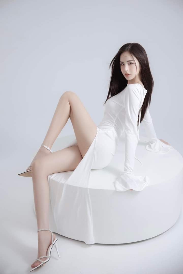 Woman in a white dress and high heels posing in a studio