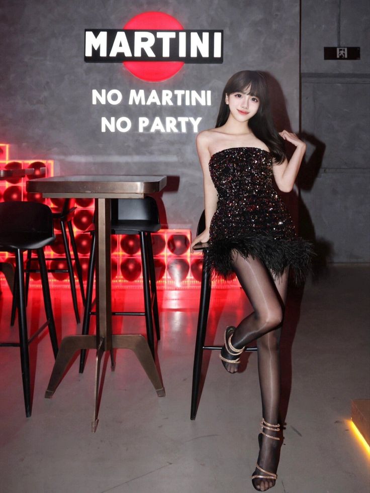 Woman in a sequin and feather dress posing in a bar with neon lighting
