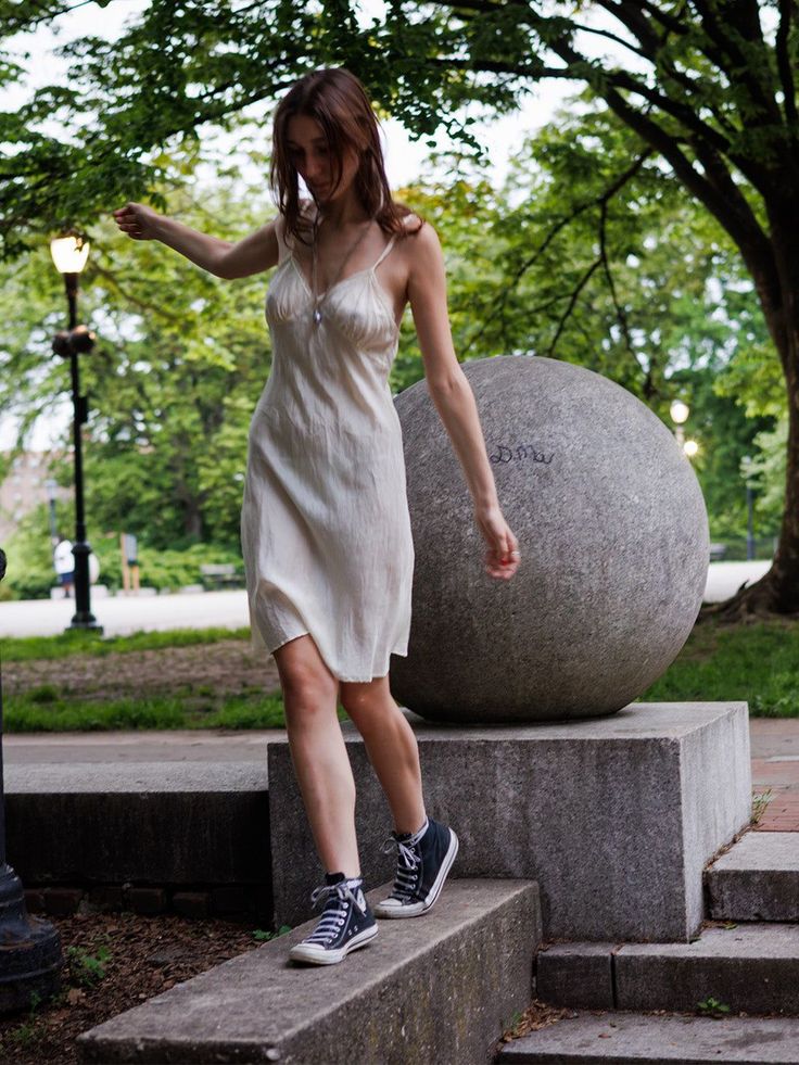 Woman in a white slip dress and sneakers walking in a park