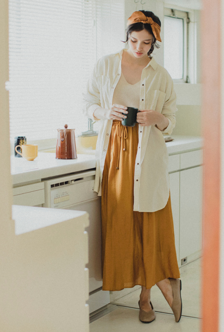 Woman in a kitchen wearing a long skirt and holding a mug