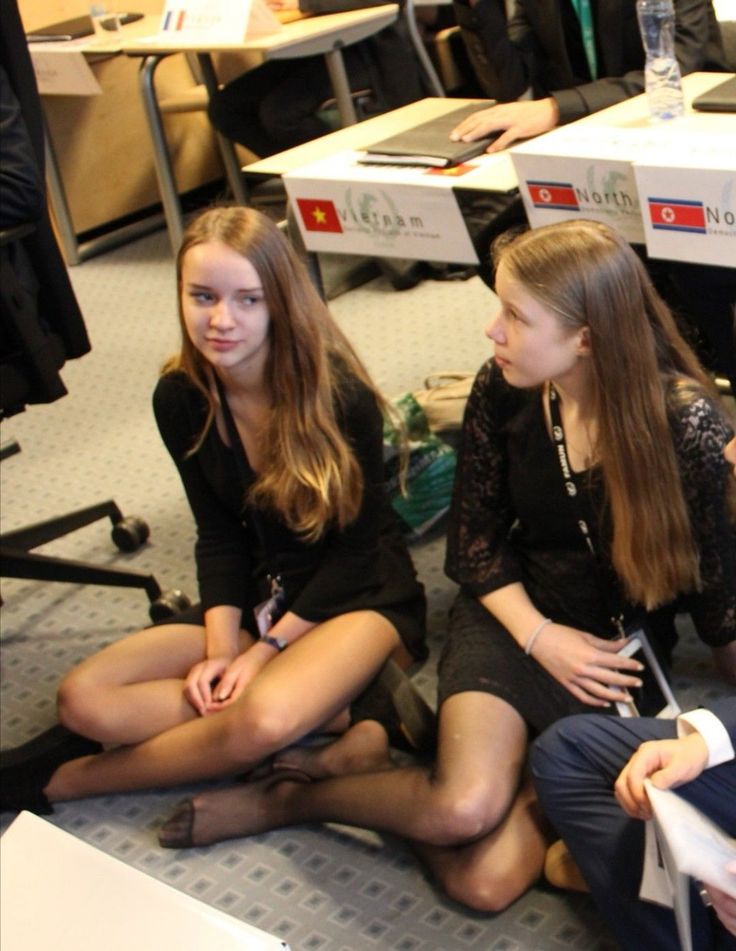 Two young women with long hair sitting on the floor at a conference