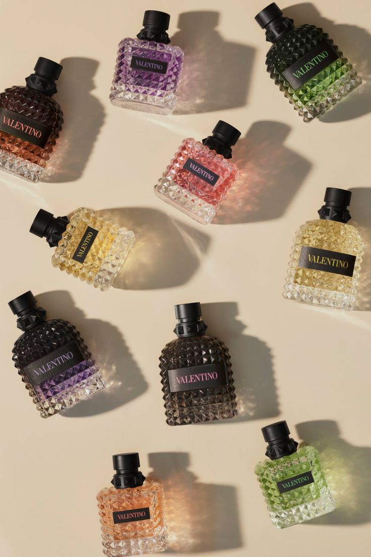 Multiple colorful perfume bottles with textured glass on a beige background