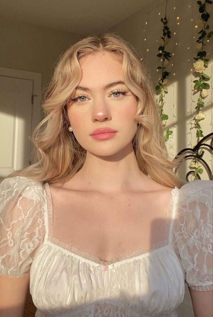 Blonde woman in a white lace top with soft lighting indoors