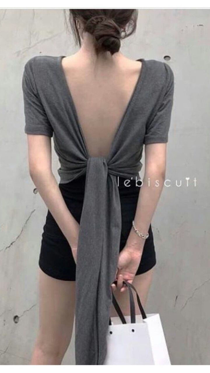 Woman in an open back top and black shorts holding a shopping bag