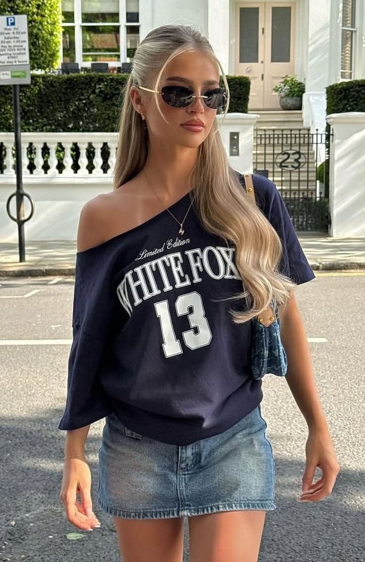 Woman with blonde hair and sunglasses wearing an off-shoulder top and denim skirt