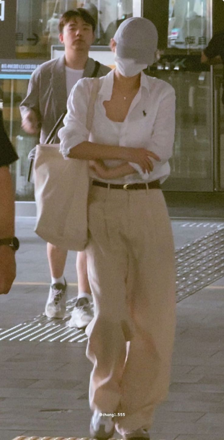 Person in a white shirt, khaki pants, and baseball cap on a street