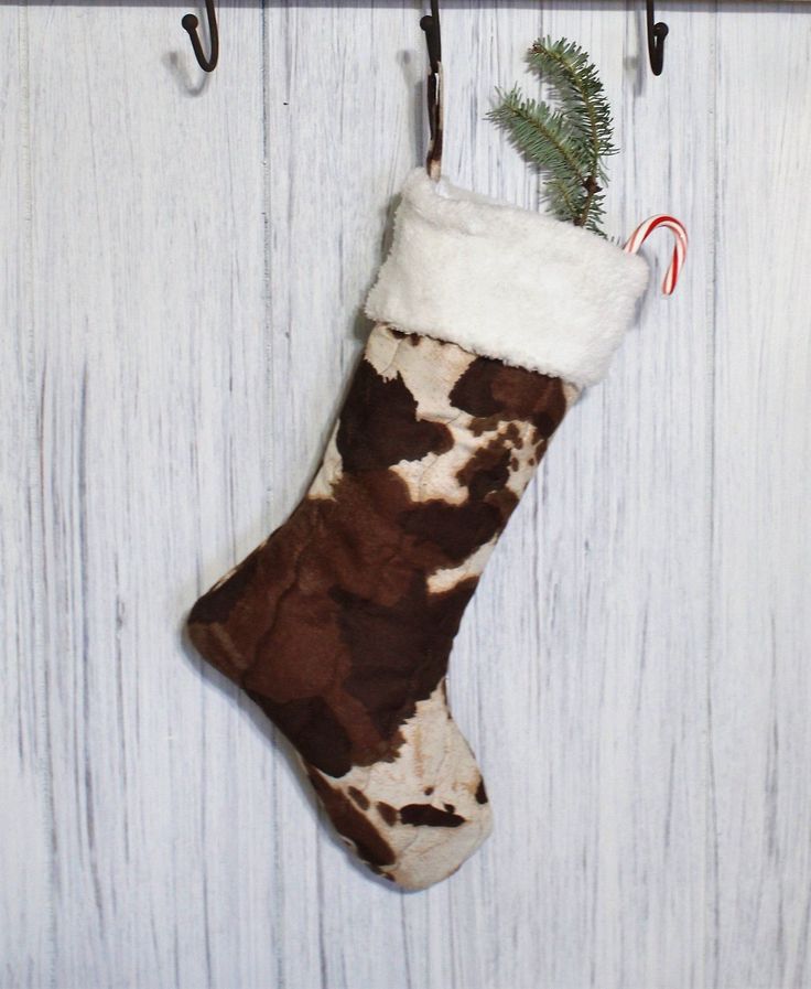 Cow print Christmas stocking with a candy cane and pine branch hanging on a wall