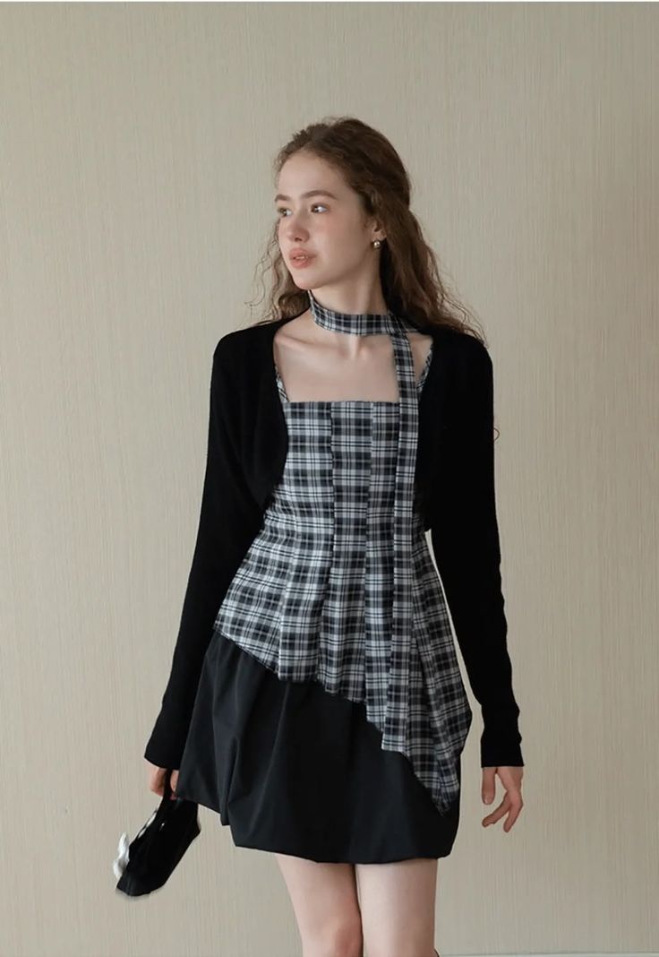 Woman in a plaid dress and black cardigan with a matching choker indoors