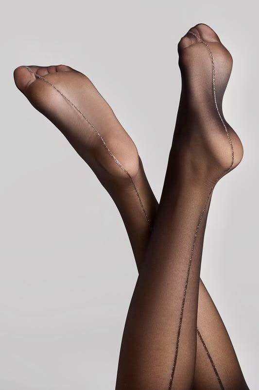 Legs in black stockings with glitter seams, crossed against a light background