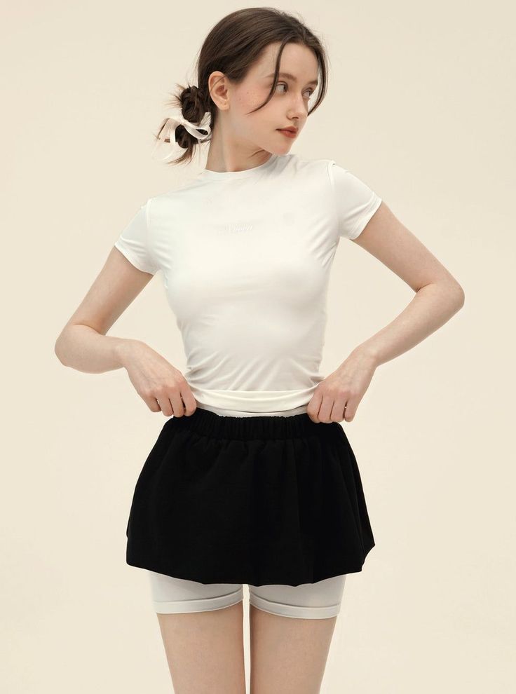 Woman in a white t-shirt and black skirt with white shorts underneath