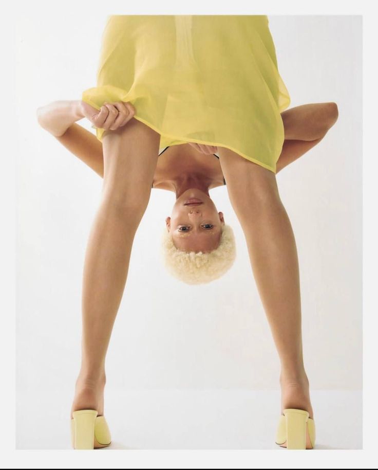 Woman in a yellow dress bending over with her head upside down