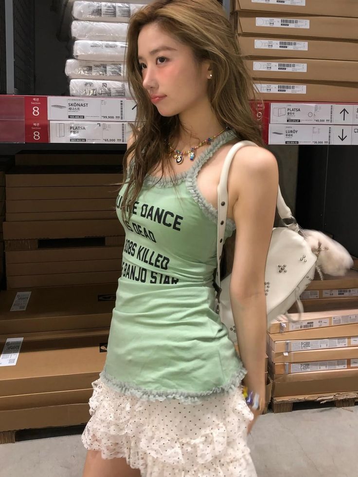 Woman with long hair wearing a green tank top and ruffle skirt indoors