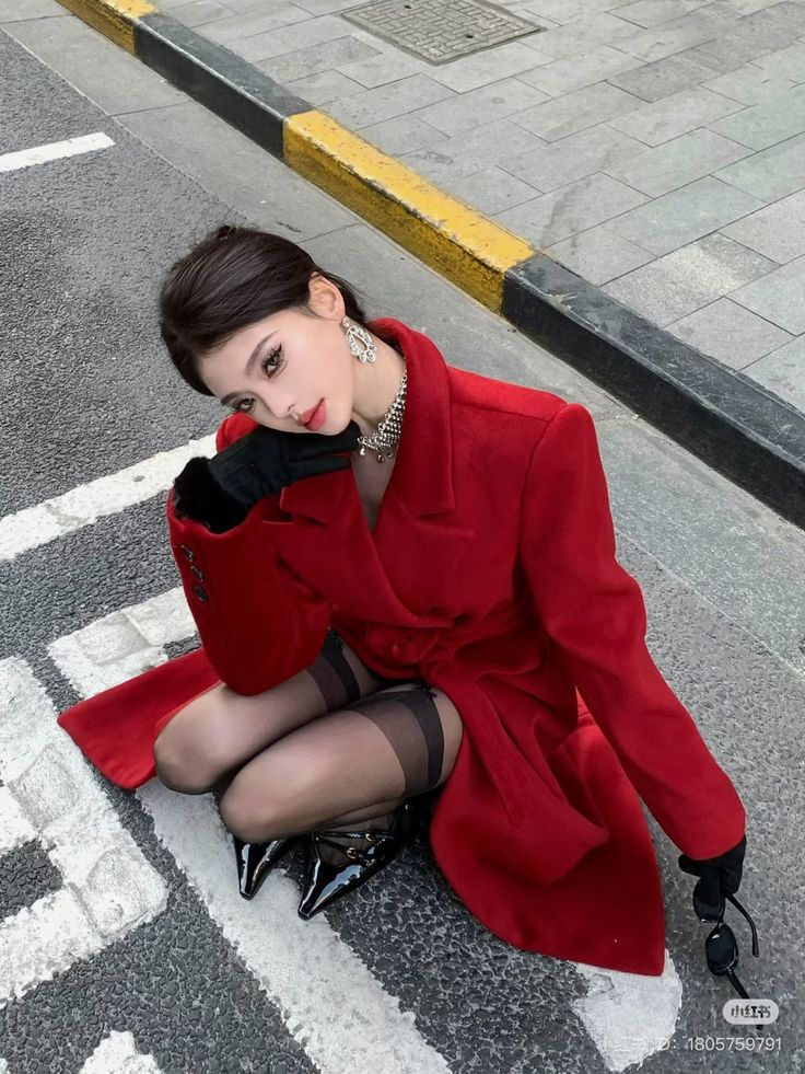 Woman in a red coat and stockings posing on a street