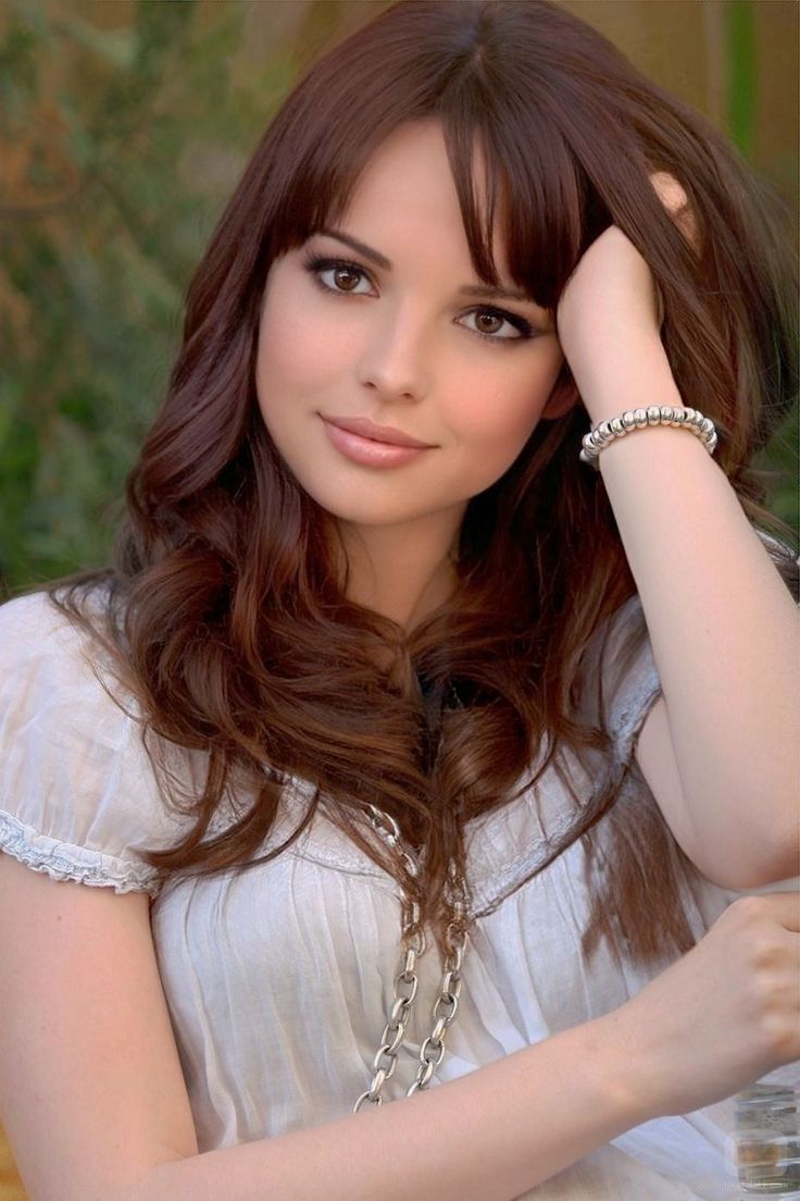 Woman with long brown hair wearing a white shirt and silver bracelet