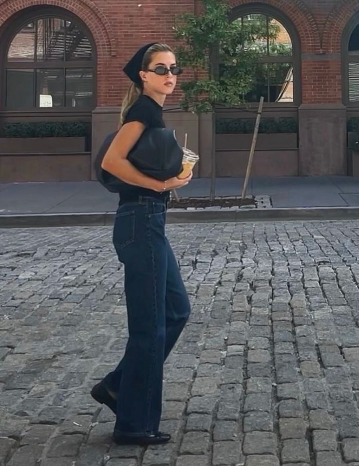 Woman with blonde hair and sunglasses walking on a cobblestone street