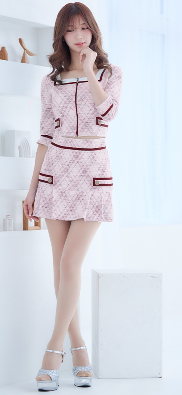 Woman in a pink tweed top and mini skirt with high heels indoors