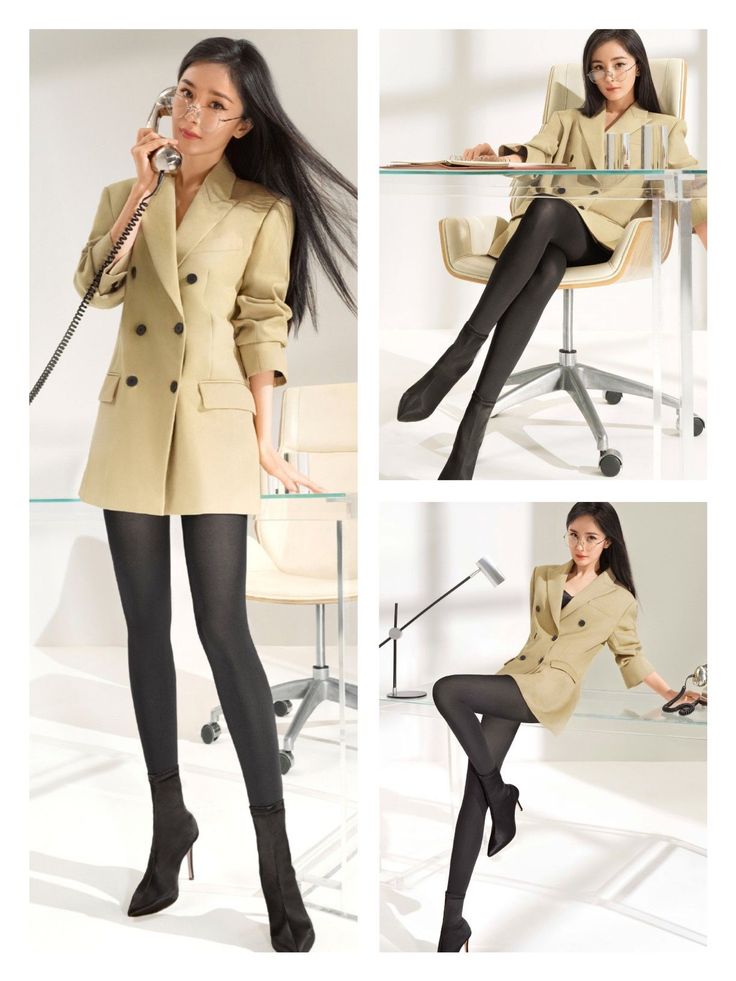 Woman in a blazer dress and black tights posing in a studio with office furniture