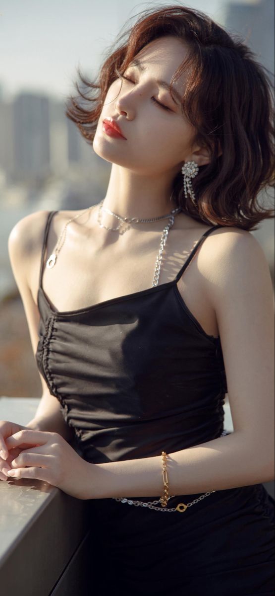 Woman in a black dress with short hair and jewelry outdoors