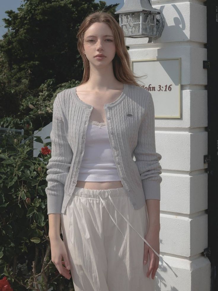 Young woman with long hair wearing a cardigan and white pants outdoors
