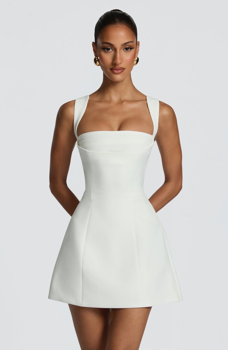 Woman in a white dress with gold earrings posing in a studio