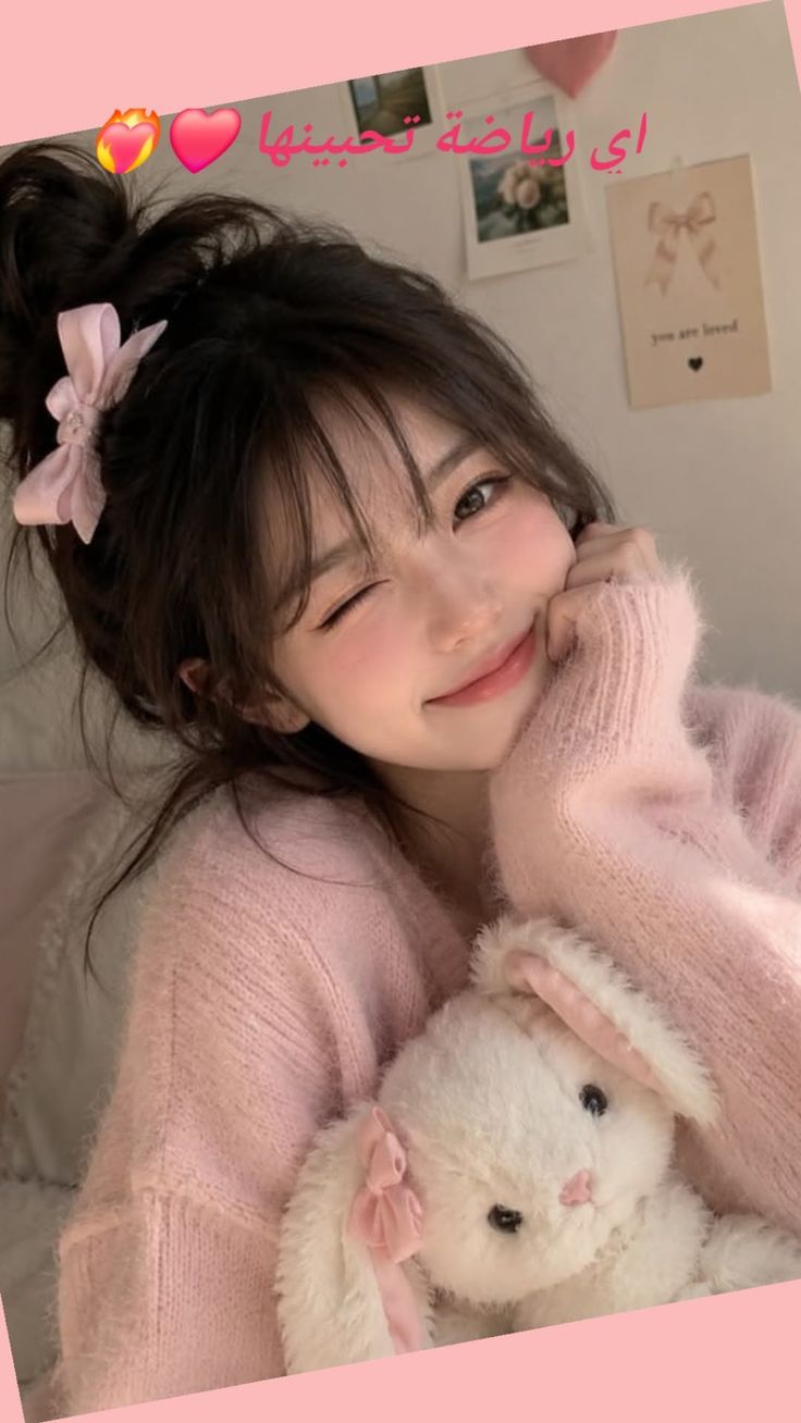 Woman in a pink sweater holding a stuffed bunny, winking at the camera