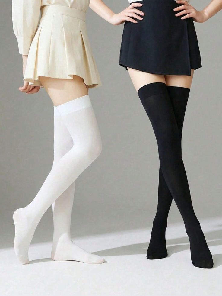 Two people wearing mini skirts and thigh-high socks in a studio setting