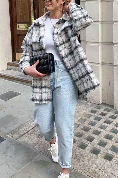 Woman in a plaid jacket, light wash jeans, and sunglasses walking on a street