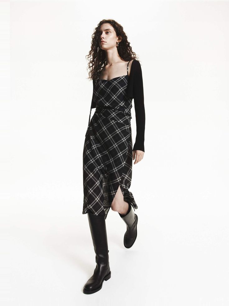 Woman in a plaid dress and black boots on a white background