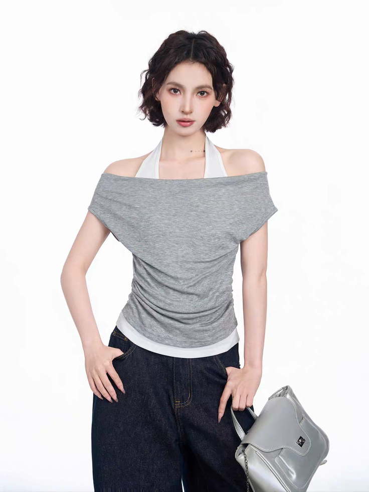 Woman with short curly hair wearing an off-shoulder top and dark jeans