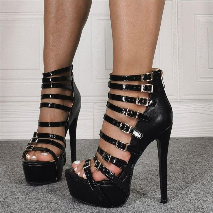 Person wearing black strappy platform high heels with buckles and white pedicure