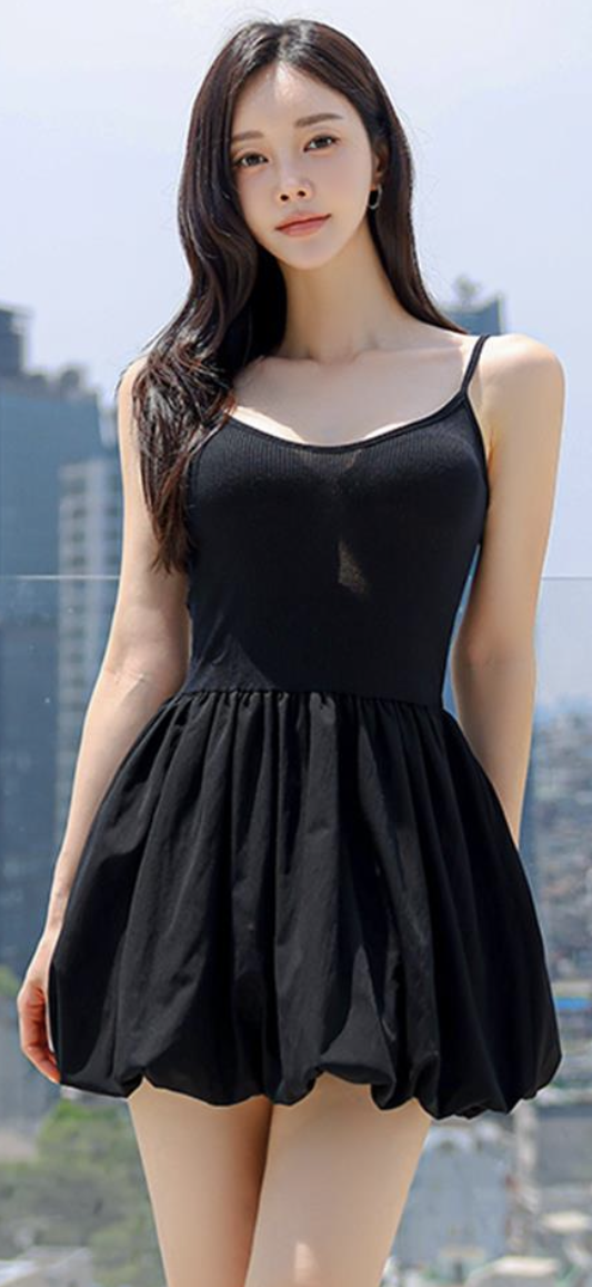 Woman in a black dress with long hair outdoors against a cityscape