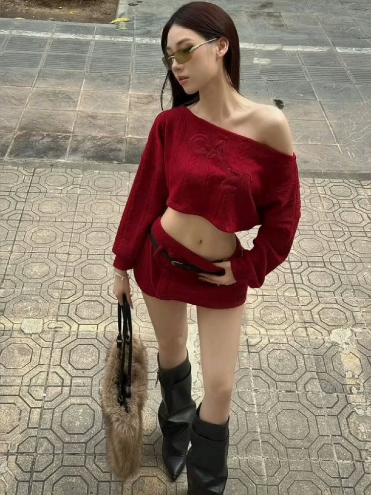 Woman in a red crop top and mini skirt with black boots and sunglasses