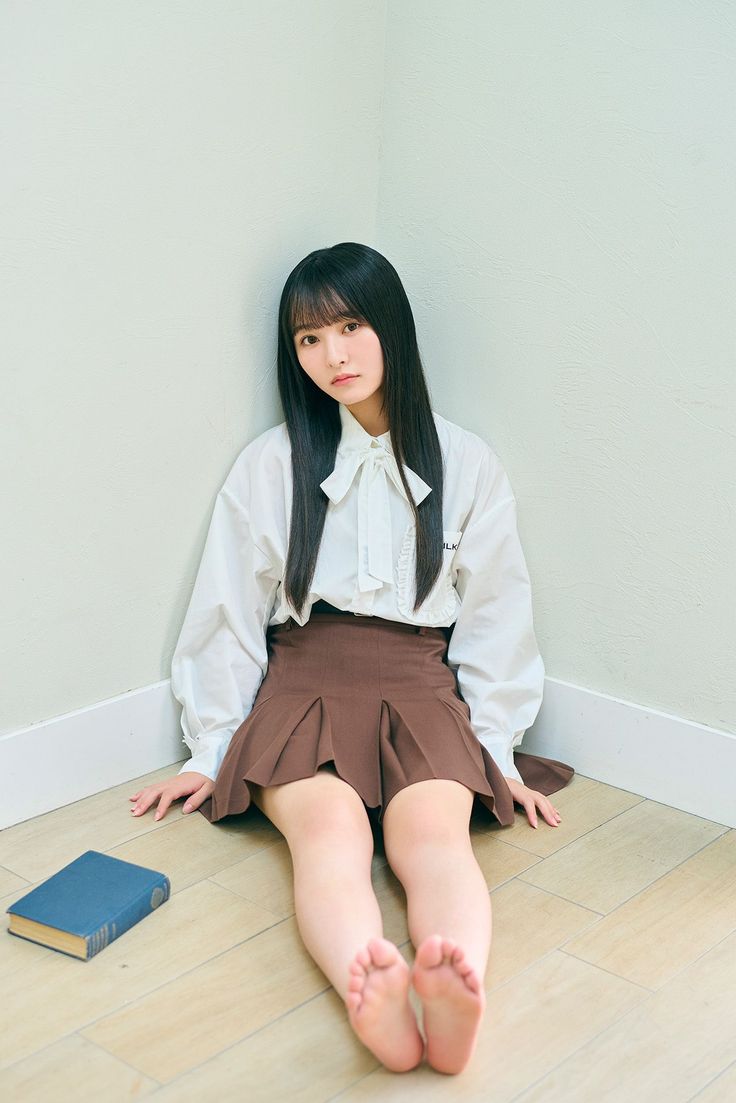 Young woman with long black hair sitting on the floor with a book