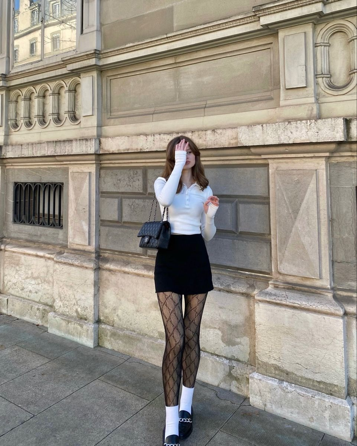 Woman in a black mini skirt and patterned tights standing outdoors