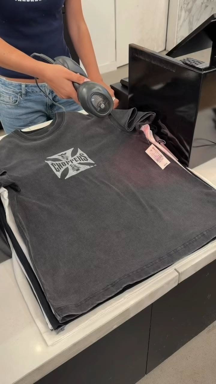 Person scanning a black t-shirt with a barcode reader at a checkout counter