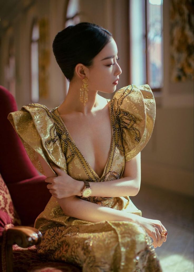 Woman in an ornate gold dress with a deep V-neck and large sleeves